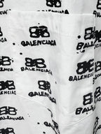 White shirt fabric close-up with black Balenciaga monogram logos and speckles