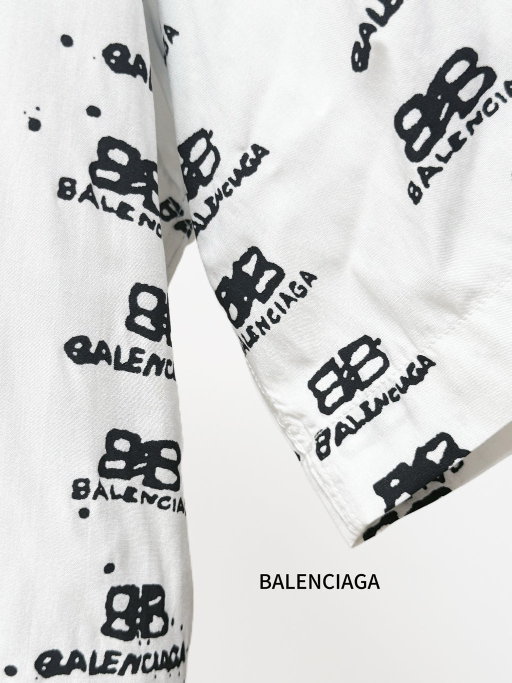 Balenciaga long-sleeve shirt cuff close-up in white with black repeating logo pattern
