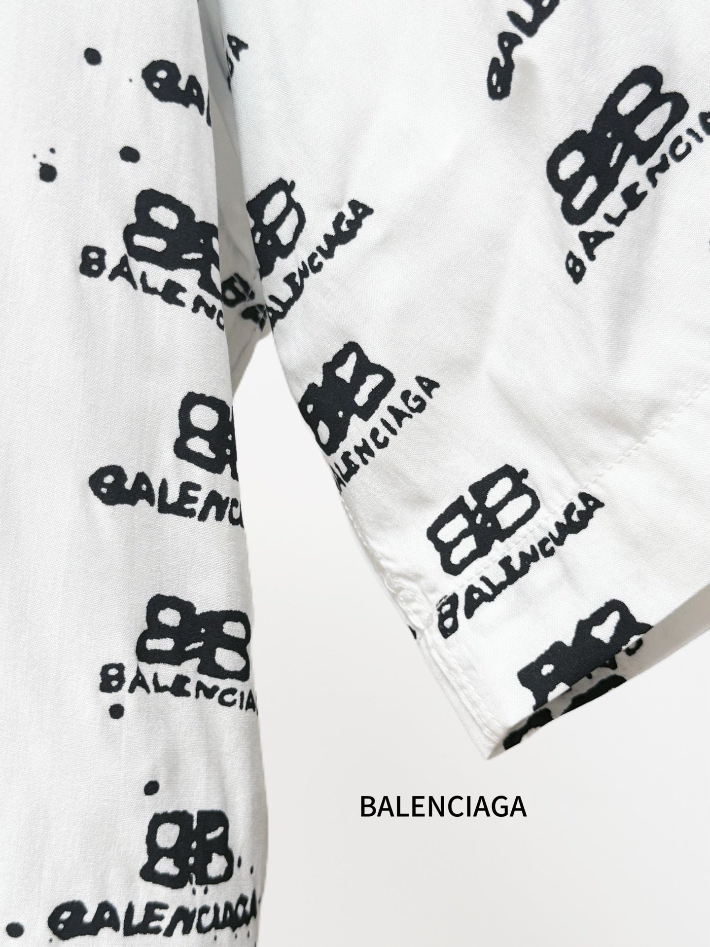 Balenciaga long-sleeve shirt cuff close-up in white with black repeating logo pattern