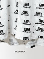Balenciaga long-sleeve shirt hem close-up in white with black logo pattern and buttons