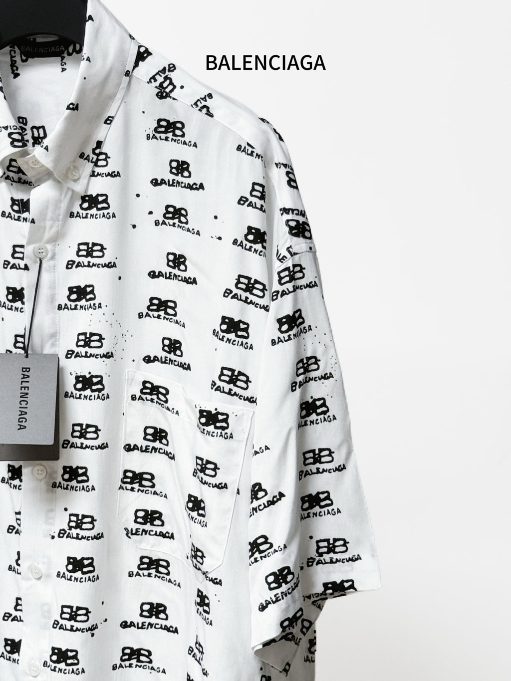 Balenciaga long-sleeve shirt close-up: white fabric with black repeating logo marks