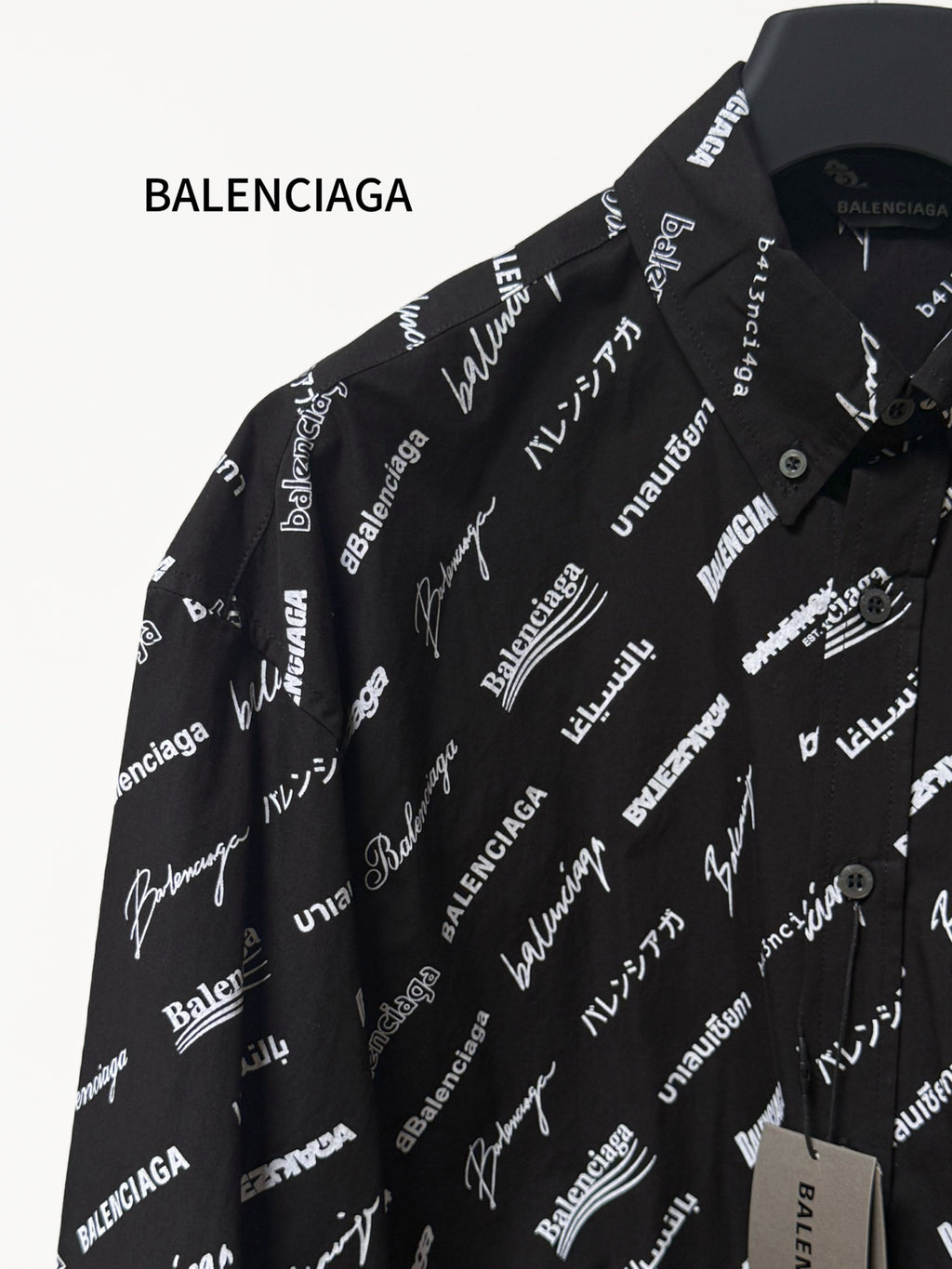 Black long-sleeve button-up shirt with repeating white script logo pattern, shoulder close-up