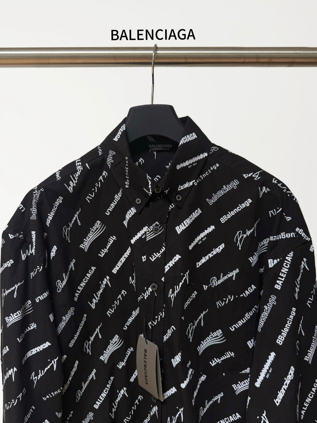 Black long-sleeve button-up shirt with repeating white script logo pattern, front close-up