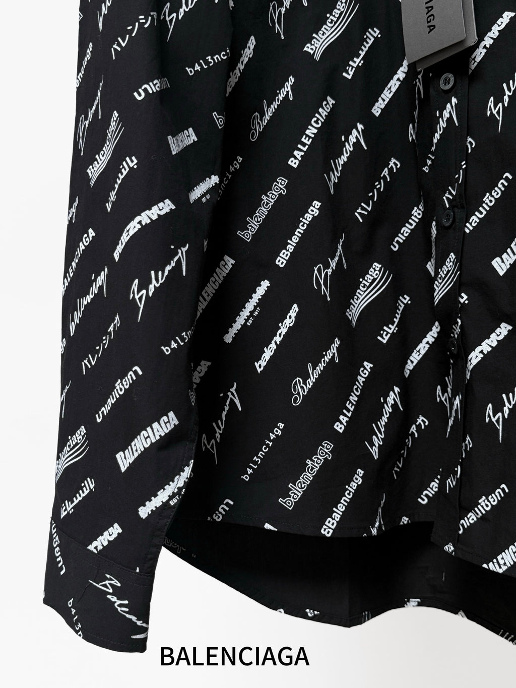 Black long-sleeve button-up shirt with repeating white script logo pattern, curved hem view
