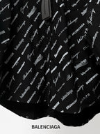 Black long-sleeve button-up shirt with repeating white script logo pattern, lower hem close-up