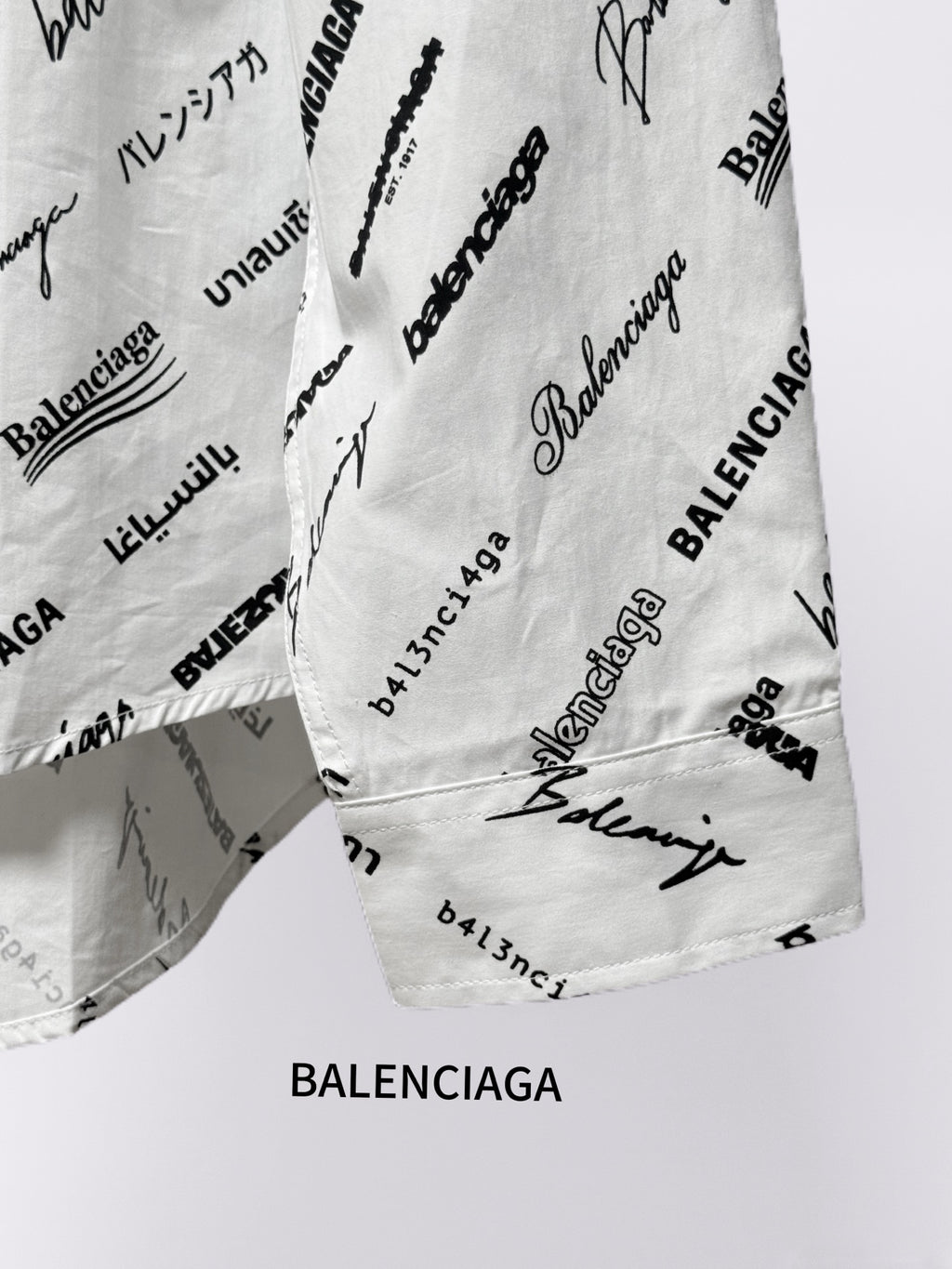 White logo-print shirt with curved hem and visible seam, angled view