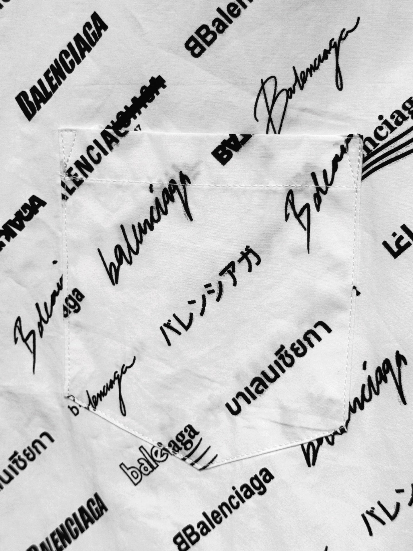 White fabric close-up with dense black BALENCIAGA-style signature and text print