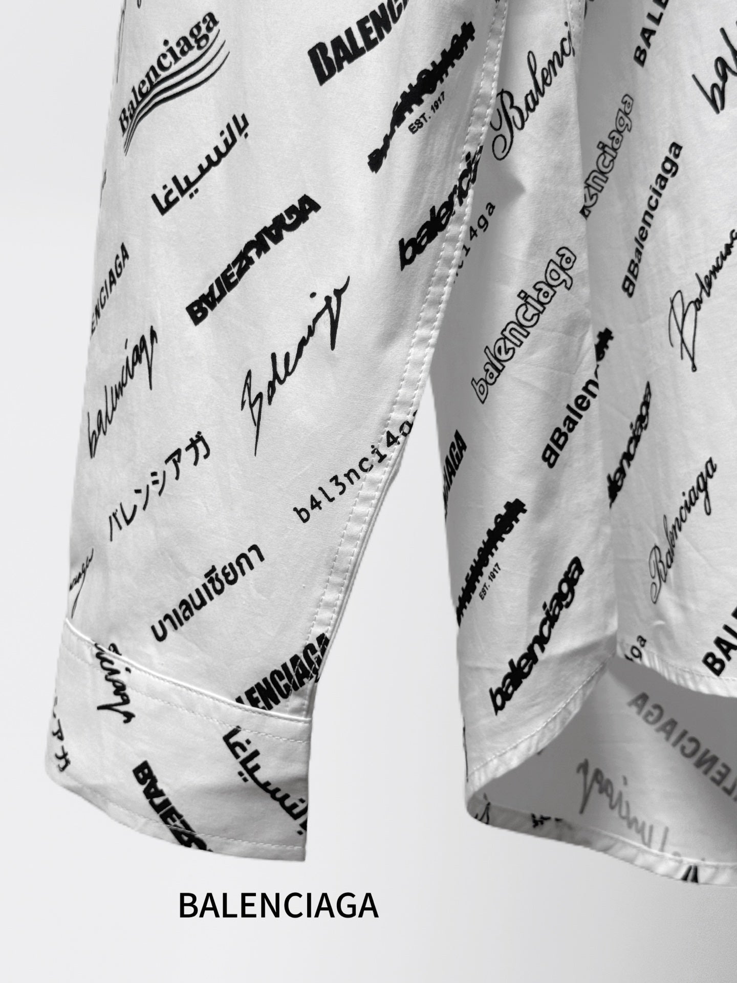 White logo-print shirt fabric close-up with black script and scattered text