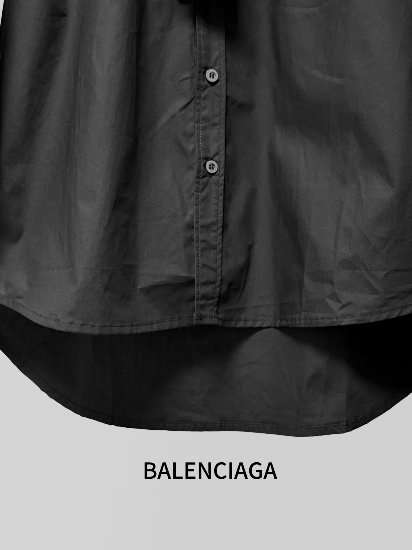 Long-sleeve button-up shirt by Balenciaga, dark black, lower button placket and hem.