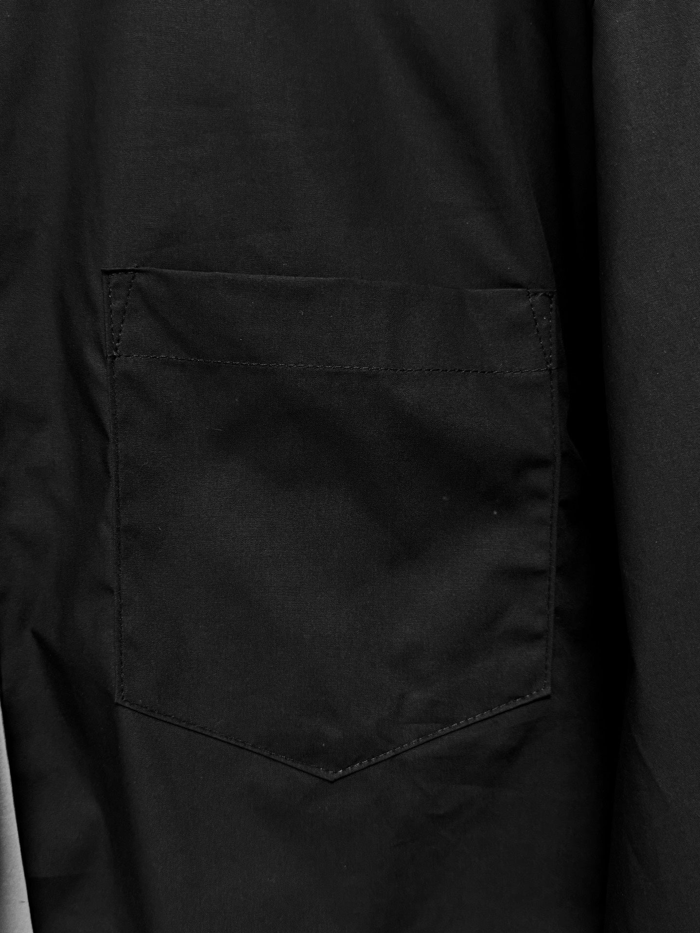 Long-sleeve button-up shirt by Balenciaga, dark black, chest pocket close-up.