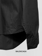 Long-sleeve button-up shirt by Balenciaga, dark black, lower side hem and drape.