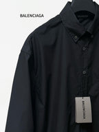 Long-sleeve button-up shirt by Balenciaga, dark black, side view with chest label tag.