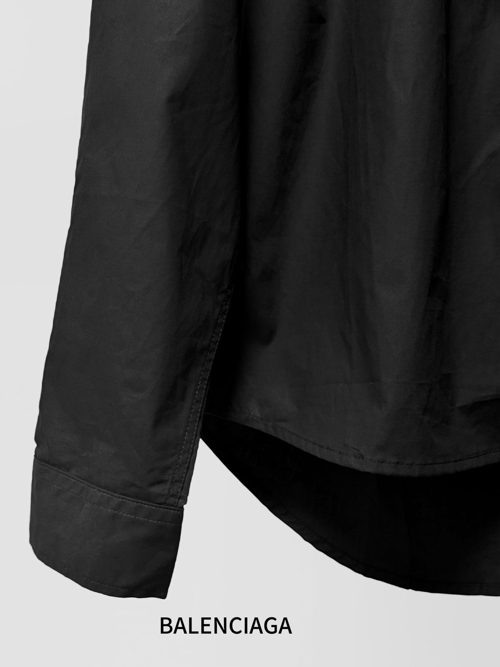 Long-sleeve button-up shirt by Balenciaga, dark black, close view of sleeve hem and cuff.