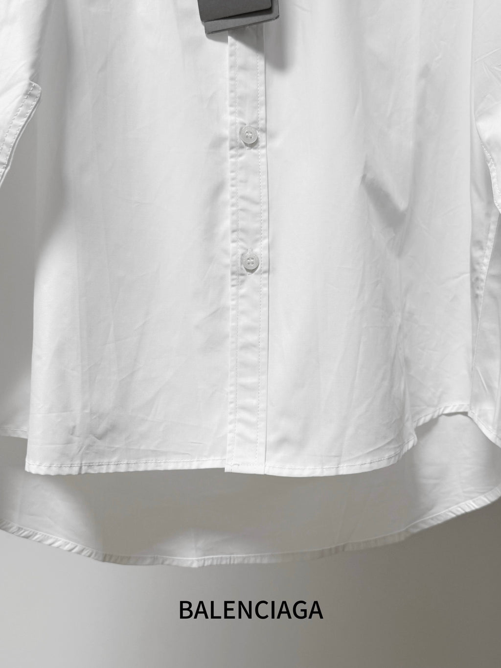Balenciaga long-sleeve button-up shirt, white, front buttons and lower hem detail.