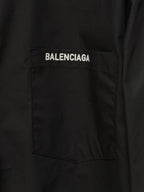 Black button-up shirt chest pocket with white Balenciaga label patch