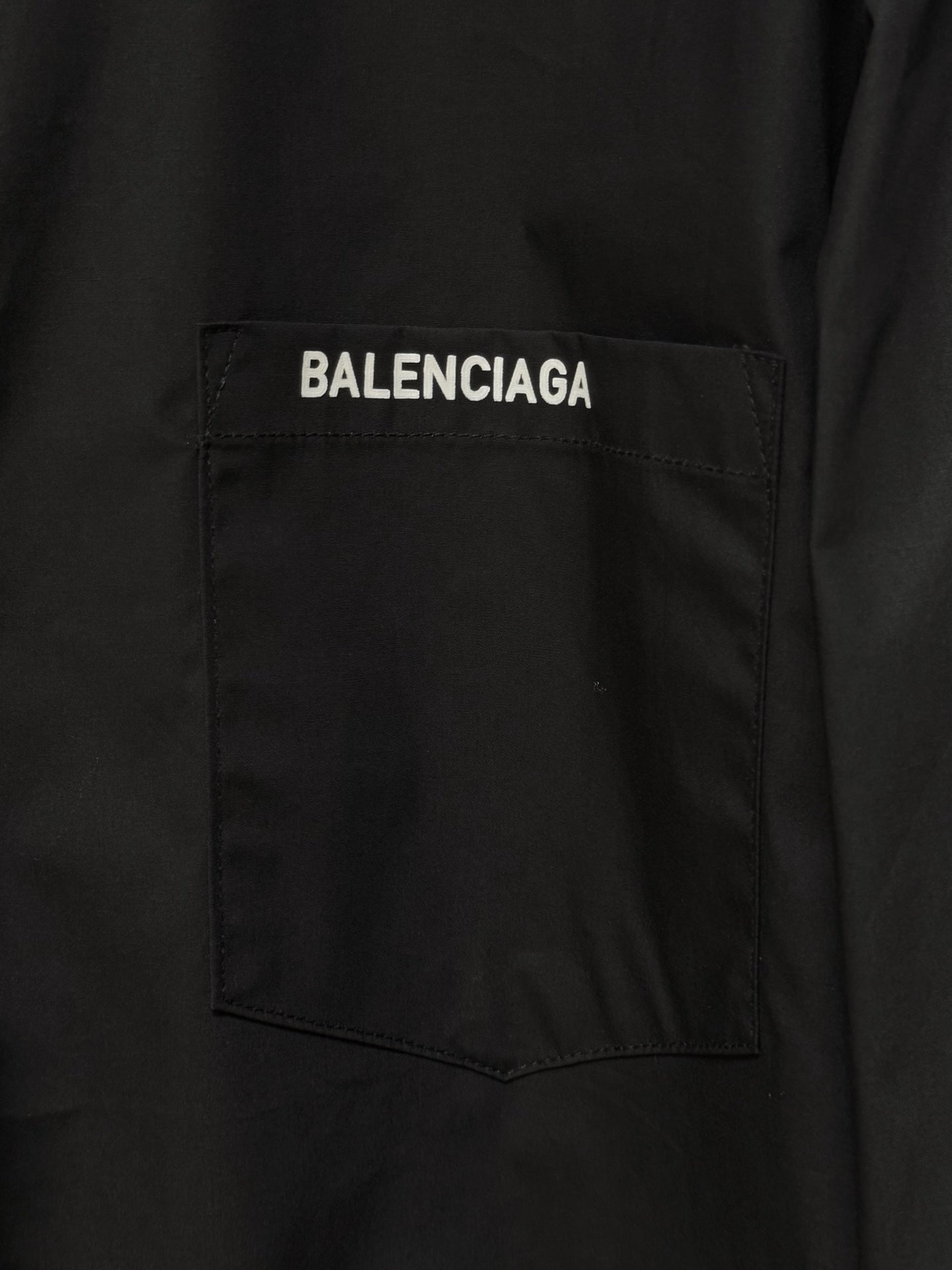 Black button-up shirt chest pocket with white Balenciaga label patch