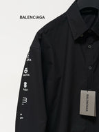 Black long-sleeve button-up shirt with printed Balenciaga sleeve text and front buttons