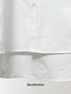 White Balenciaga button-up shirt hem with pleats and a row of visible buttons