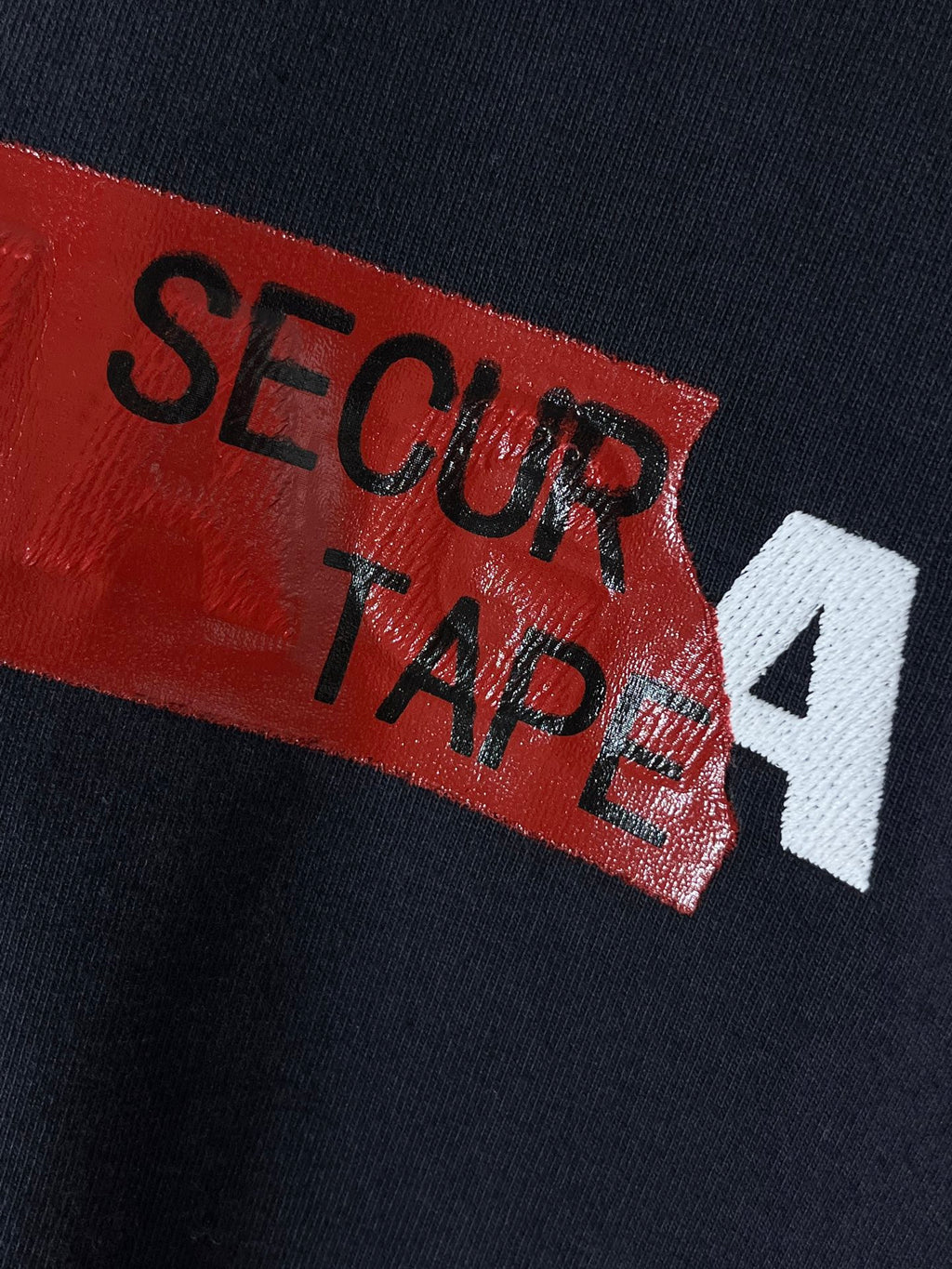 Navy T-shirt with close-up red label reading “SECUR TAPE” with white “4”