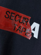 Navy T-shirt with close-up red label reading “SECUR TAPE” with white “4”