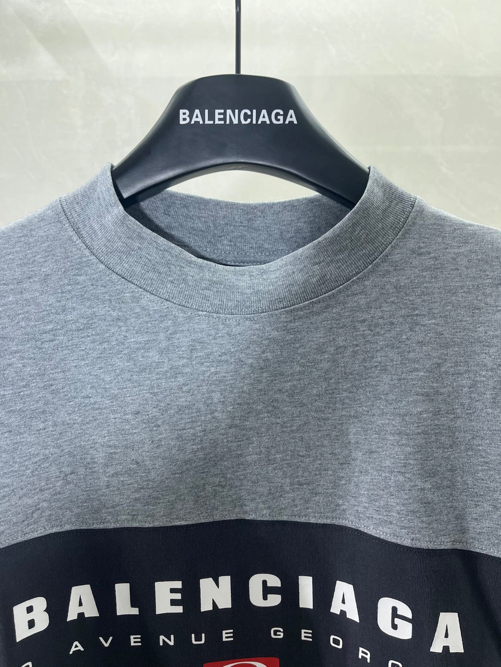 Round-neck T-shirt close-up with BALENCIAGA neck logo on gray fabric