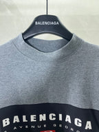 Round-neck T-shirt close-up with BALENCIAGA neck logo on gray fabric