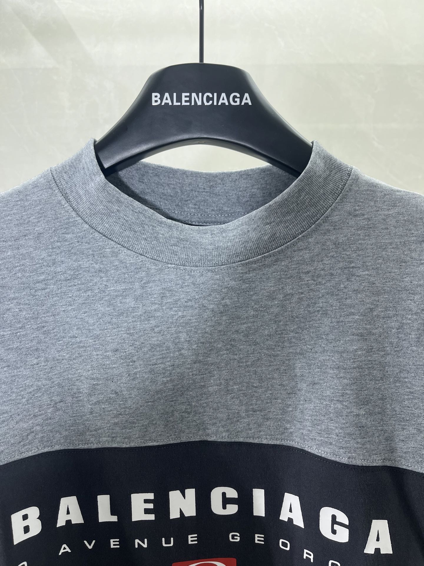 Round-neck T-shirt close-up with BALENCIAGA neck logo on gray fabric