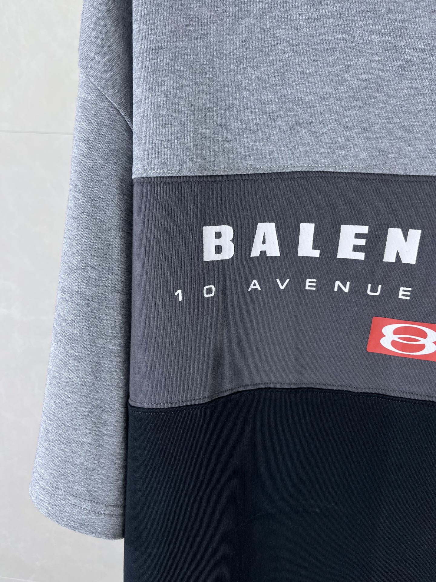 Two-tone T-shirt panel close-up with BALENCIAGA text and red logo patch