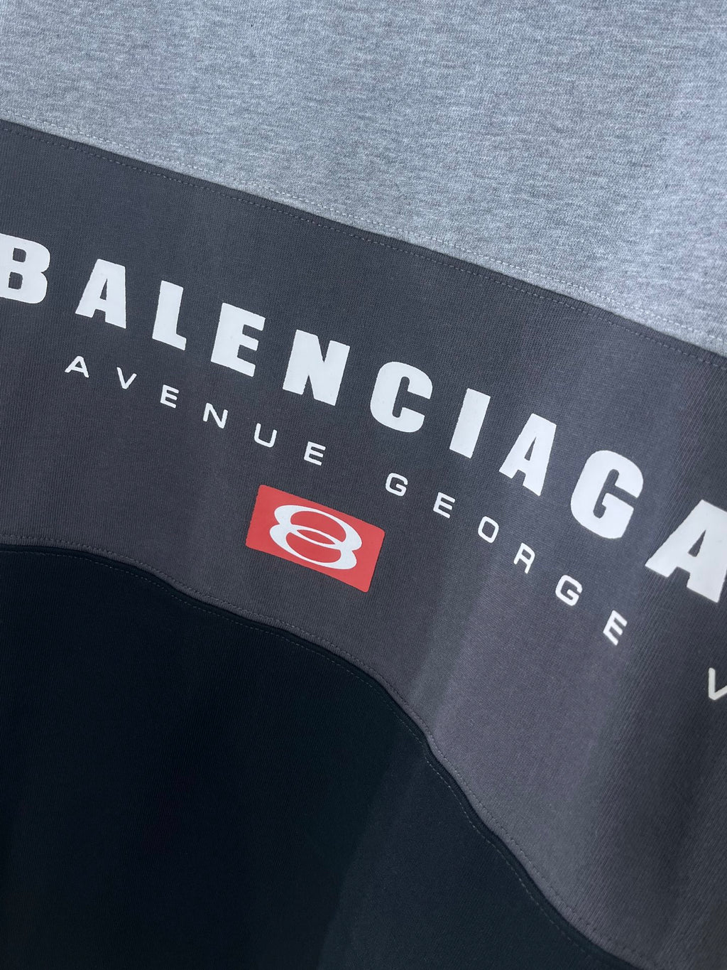 Two-tone T-shirt close-up with BALENCIAGA text and red emblem patch