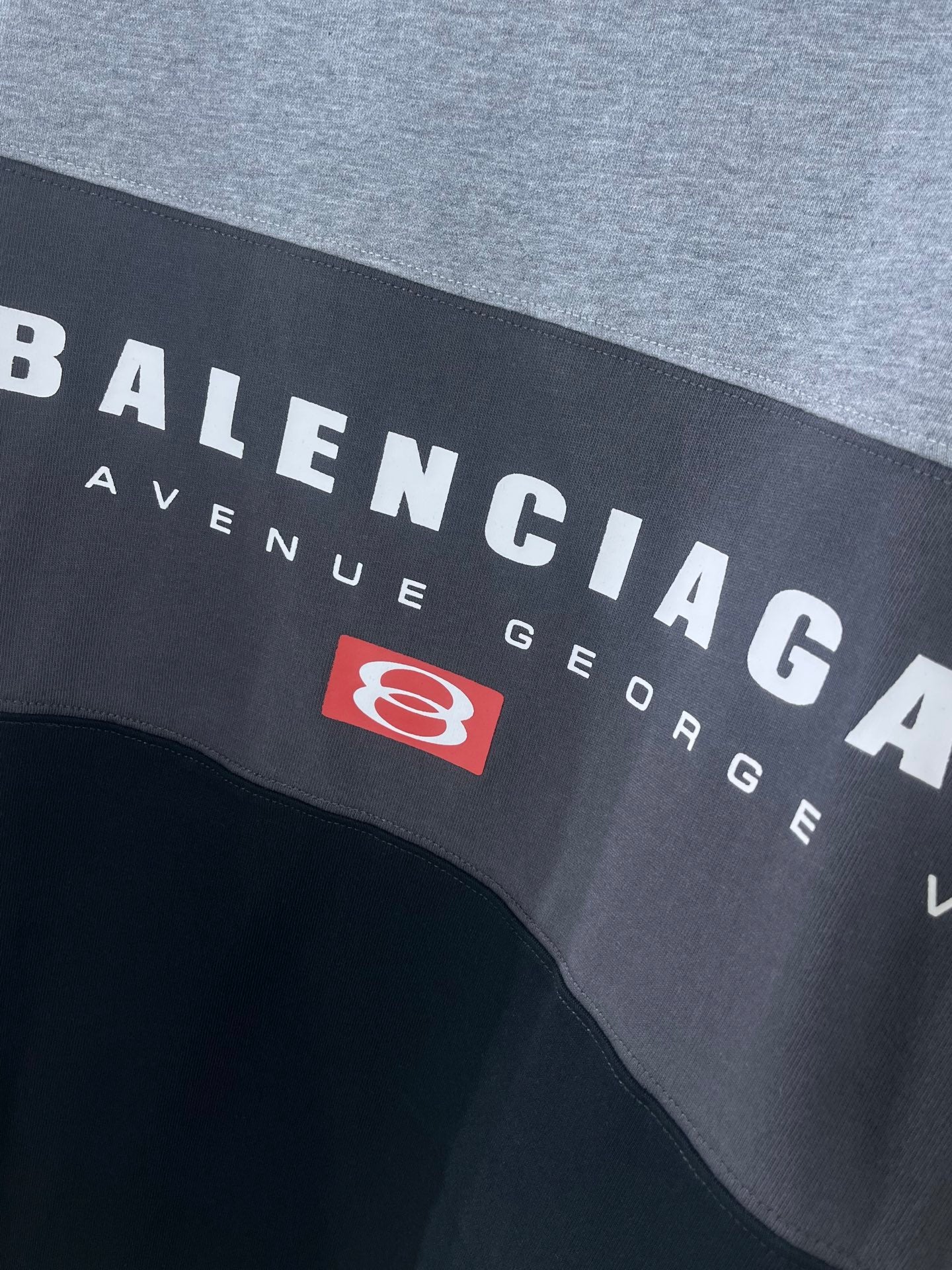 Two-tone T-shirt close-up with BALENCIAGA text and red emblem patch