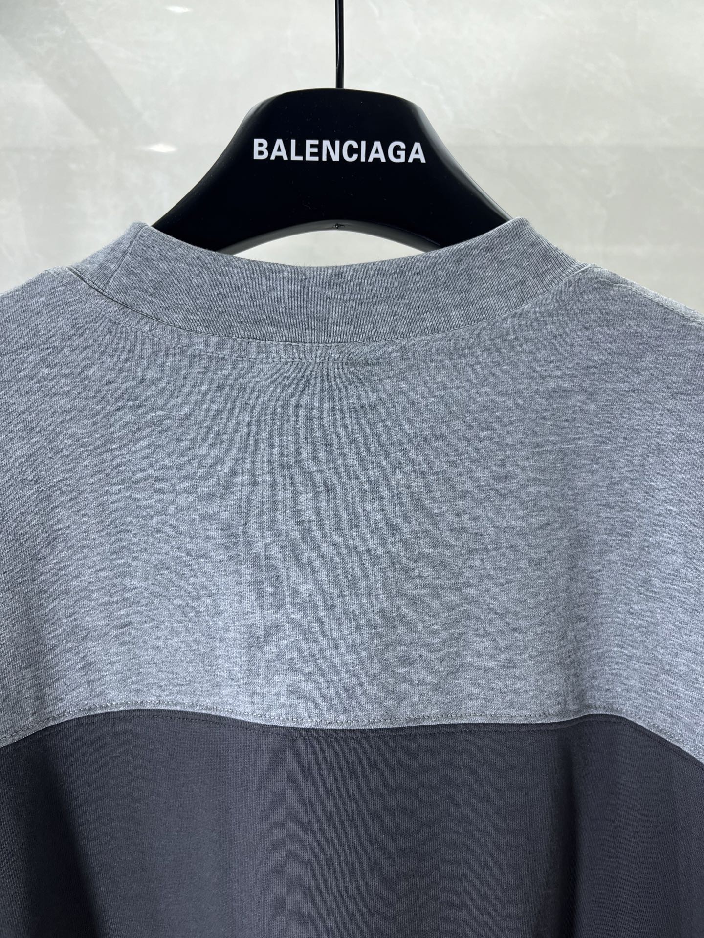 Back of two-tone short-sleeve T-shirt in gray and black with neck logo print