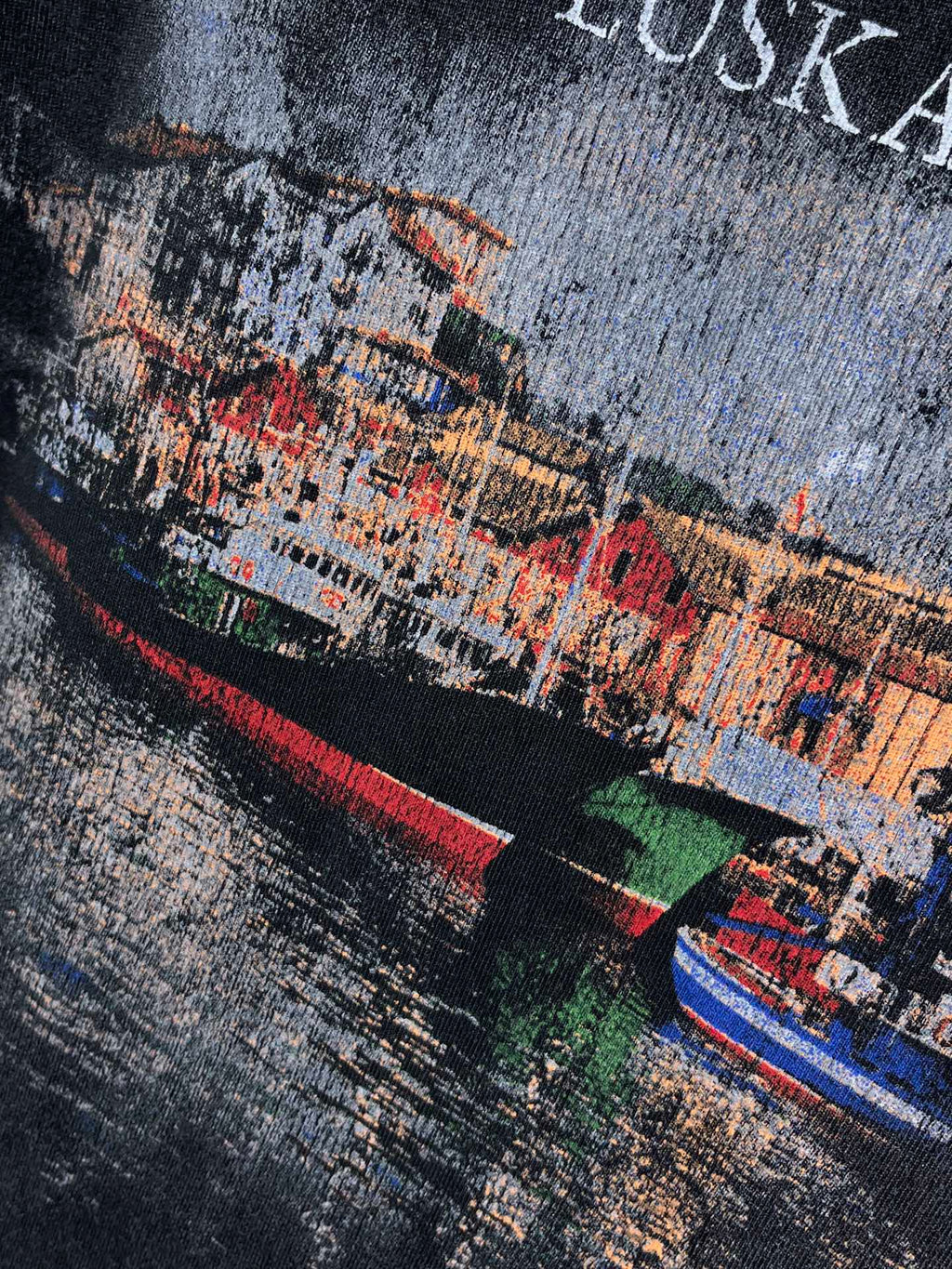 Navy T-shirt close-up of multicolor EUSKADI cityscape with curved red/green bands.