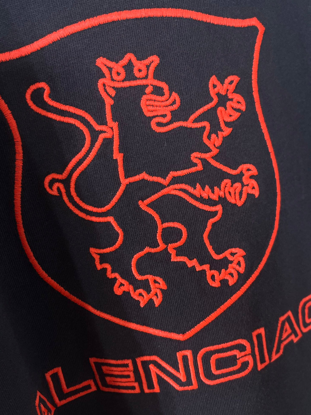 Navy Balenciaga T-shirt close-up of large red shield and 'BALENCIAGA' text