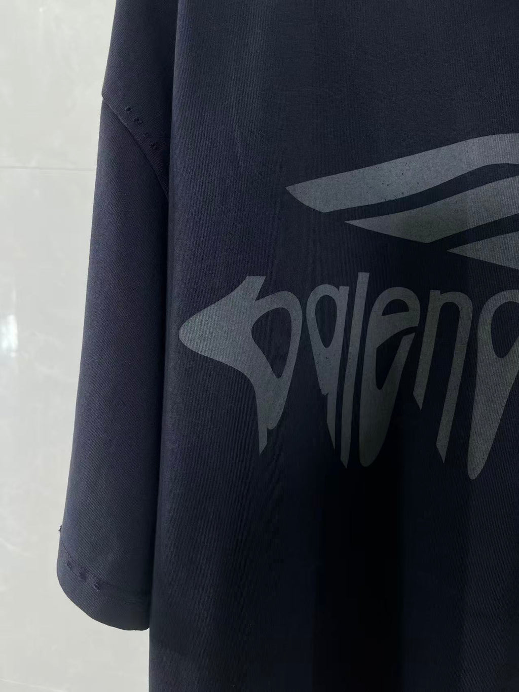 Navy Balenciaga T-shirt sleeve and chest logo graphic in close-up.