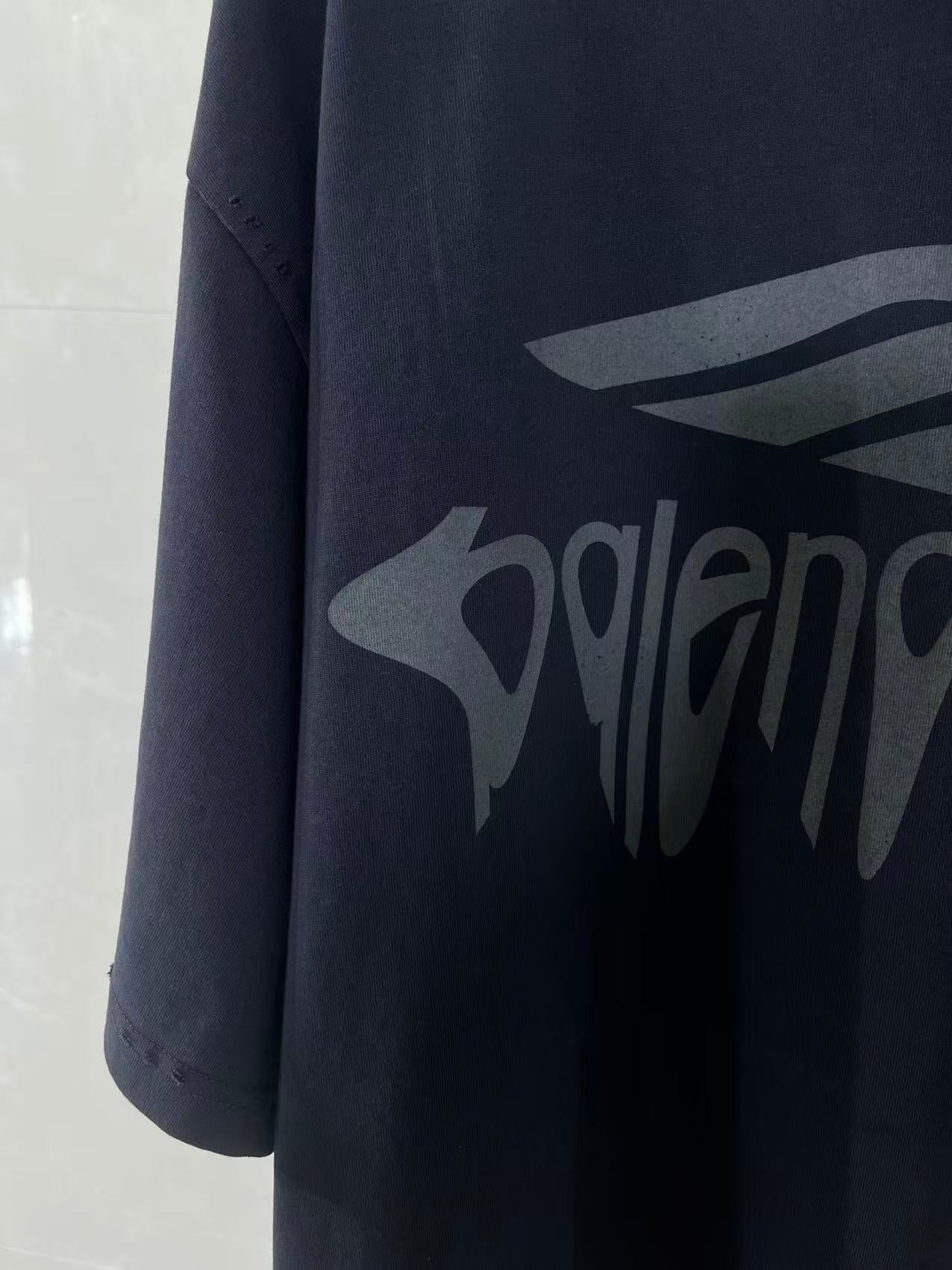 Navy Balenciaga T-shirt sleeve and chest logo graphic in close-up.