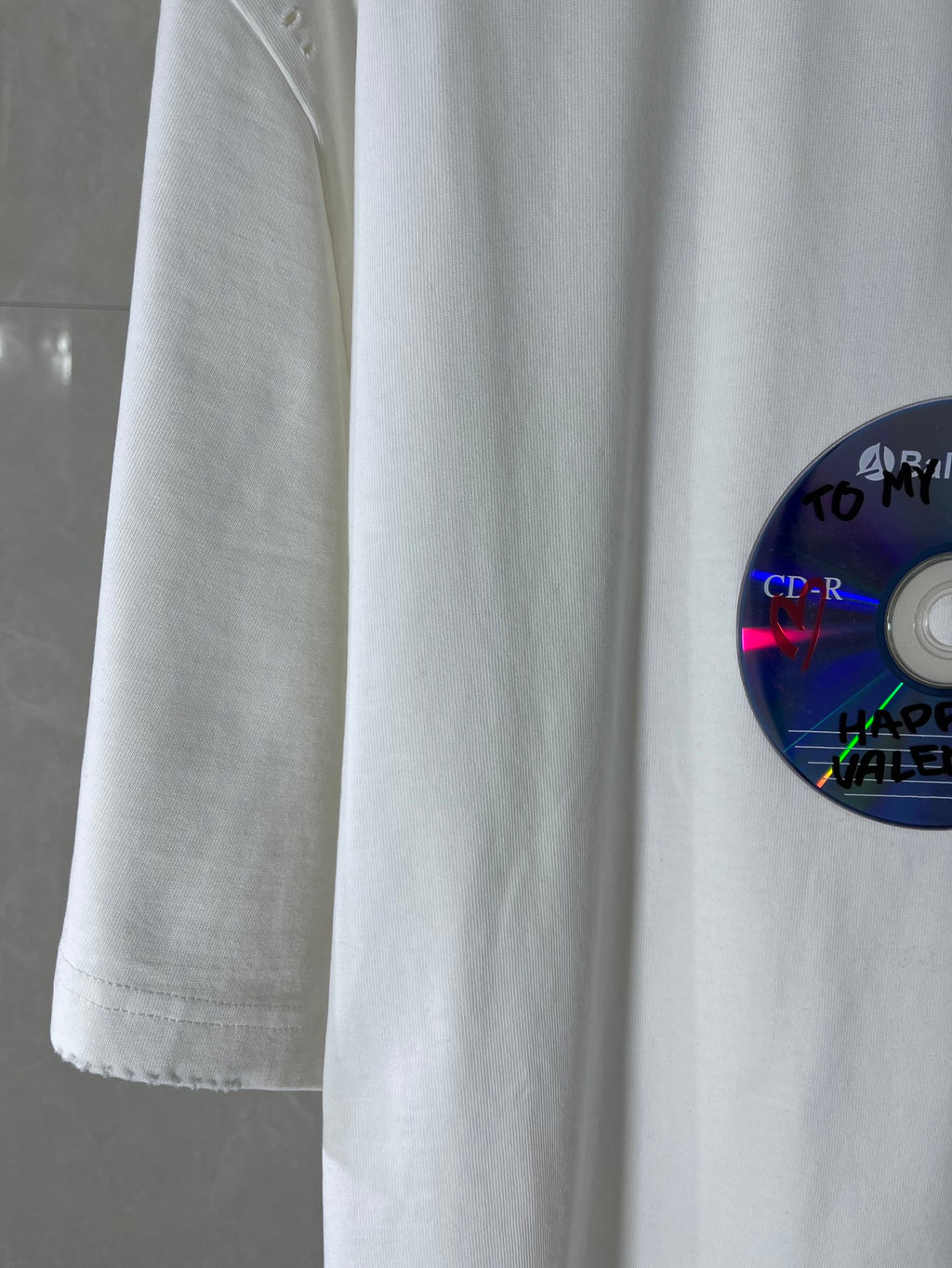 White Balenciaga T-shirt sleeve and side seam detail with part of the disc graphic