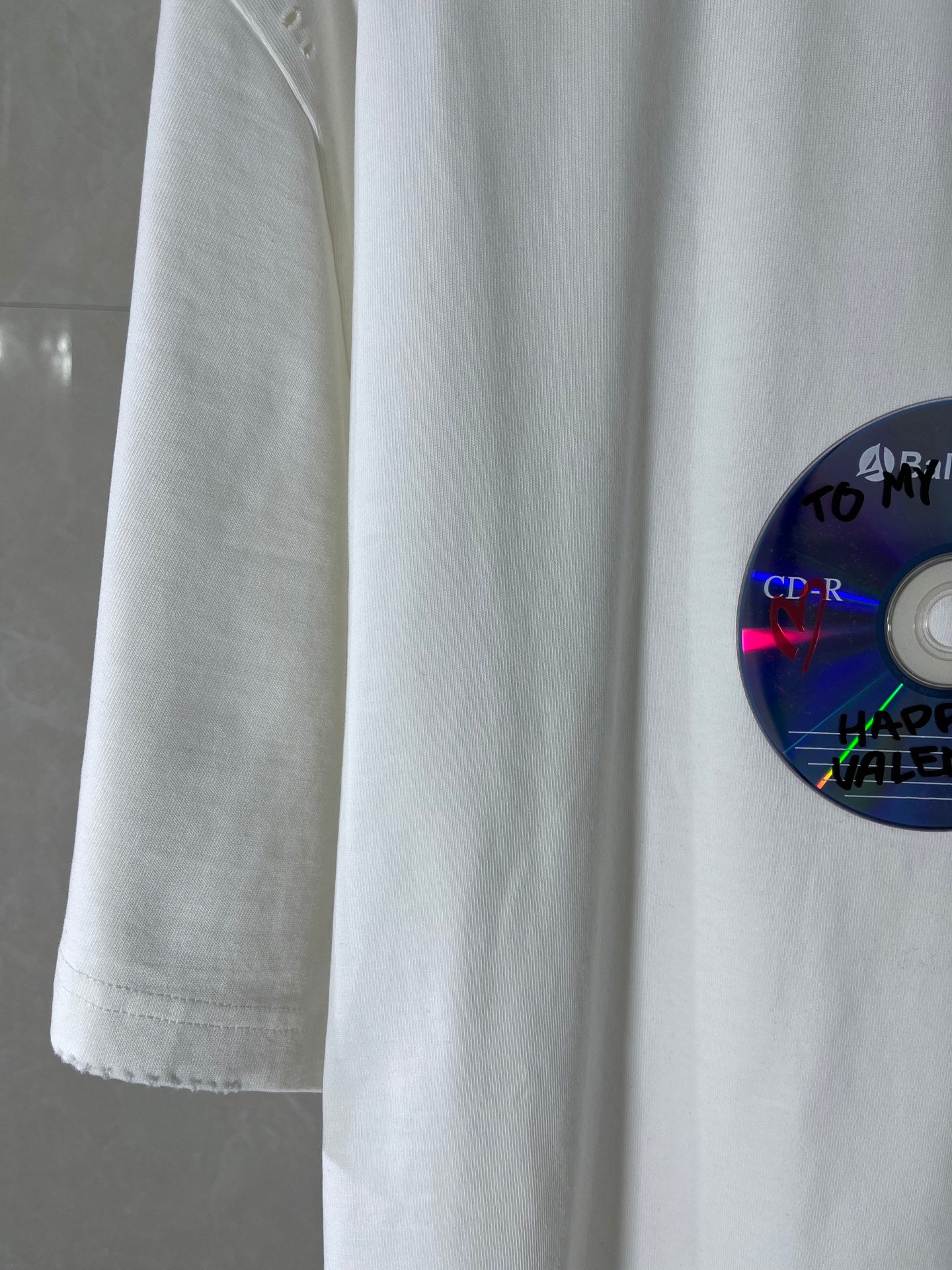 White Balenciaga T-shirt sleeve and side seam detail with part of the disc graphic