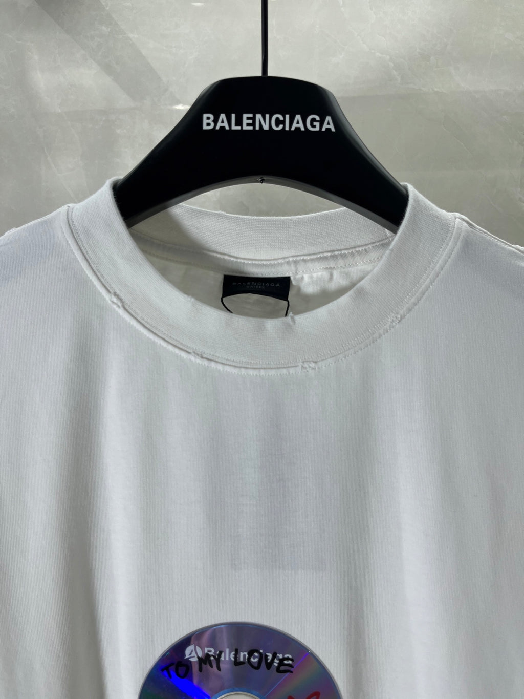 White Balenciaga T-shirt neckline with black label and part of the colorful disc graphic