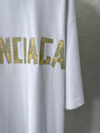 White Balenciaga T-shirt with partial gold text graphic on chest and side hem