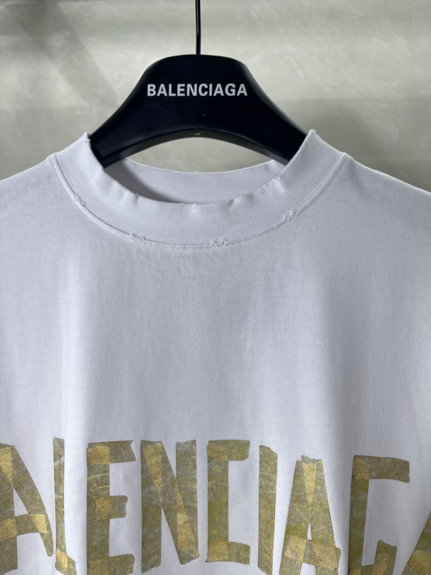 White crewneck Balenciaga T-shirt close-up of neckline and gold text print