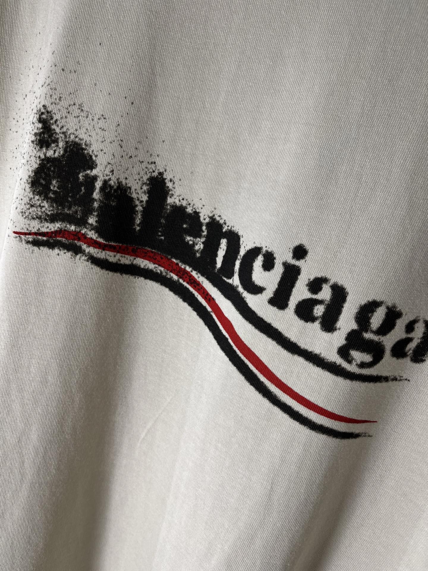 Balenciaga light cream T-shirt close-up of logo lettering with red and black stripe
