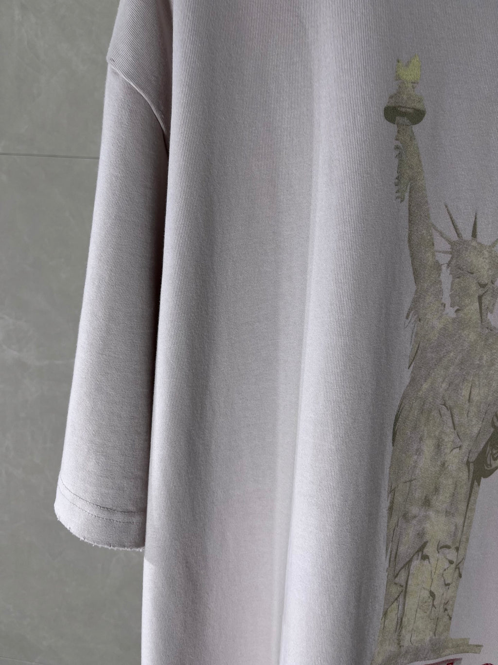 White Balenciaga T-shirt sleeve and side seam with partial statue graphic