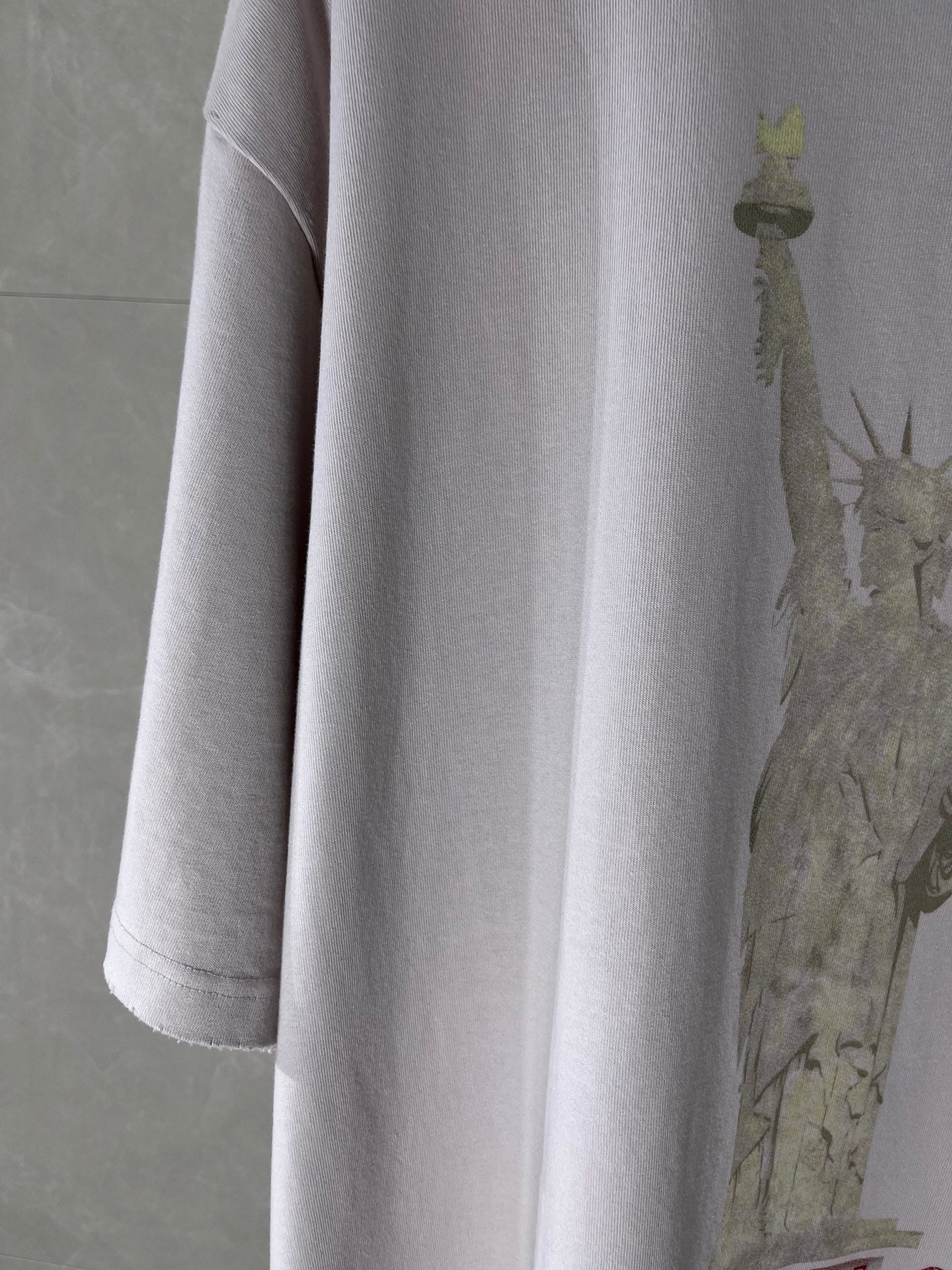 White Balenciaga T-shirt sleeve and side seam with partial statue graphic