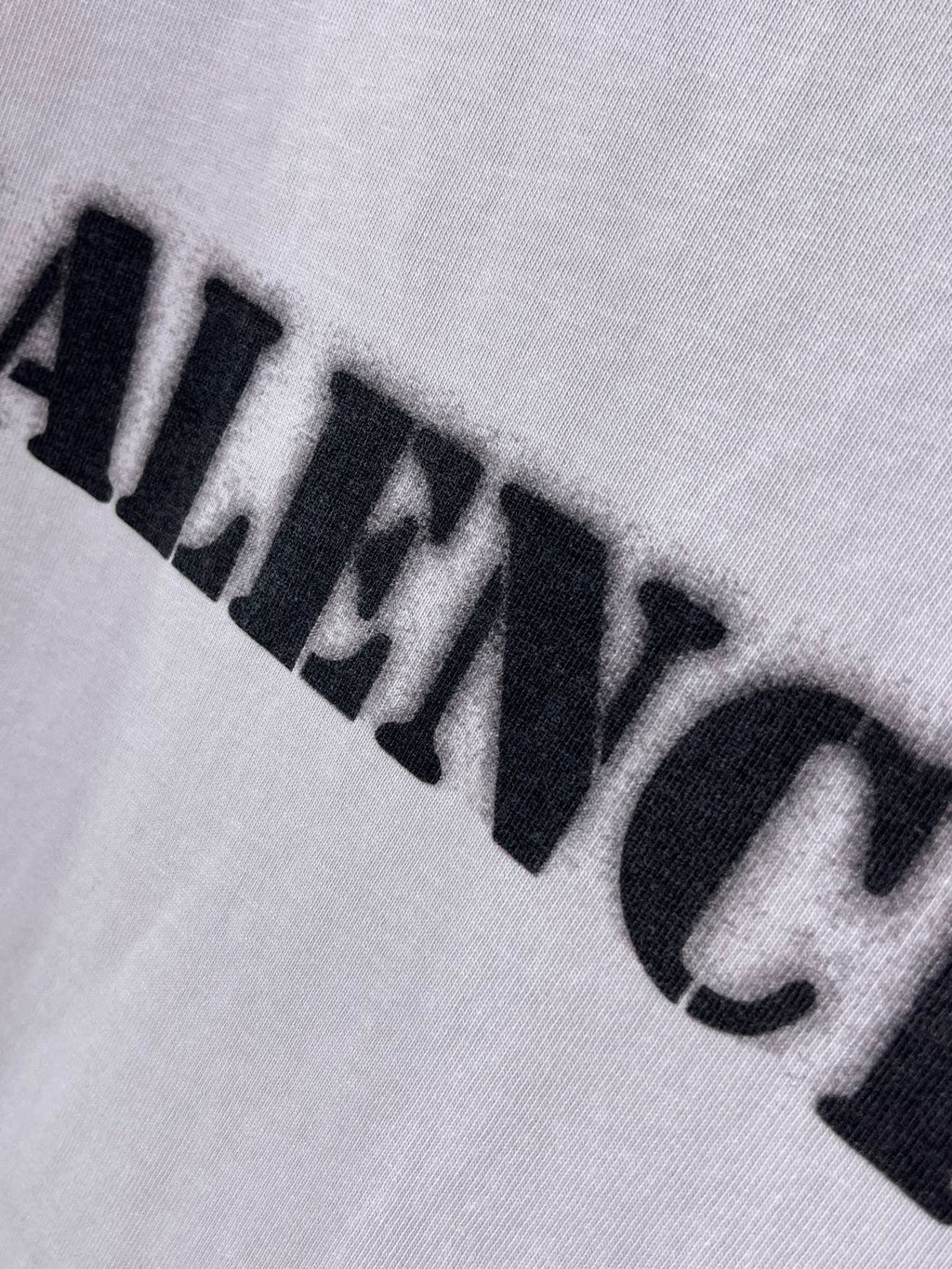 Light lavender Balenciaga T-shirt close-up of black logo print across fabric