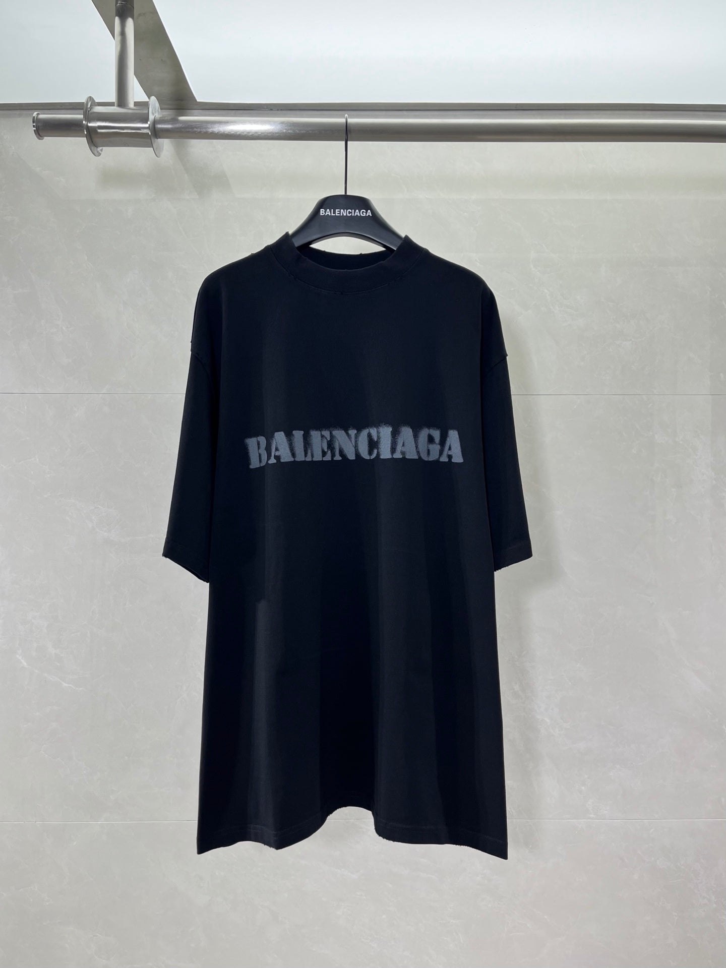Dark oversized T-shirt with BALENCIAGA logo centered on front.