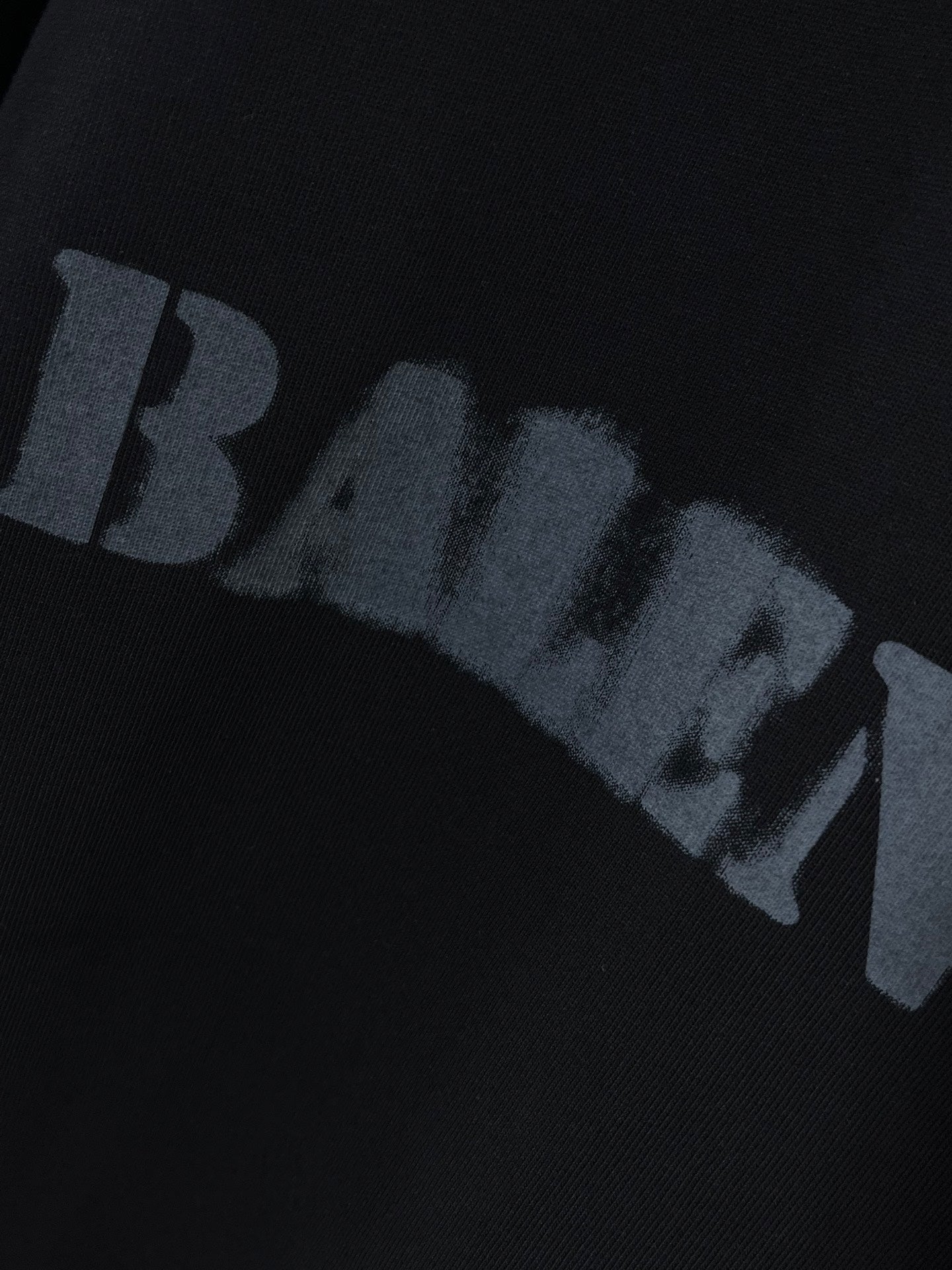 Dark T-shirt with BALENCIAGA logo print across sleeve area.