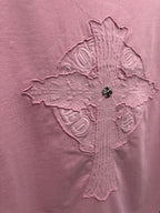 Pink T-shirt close-up of raised cross emblem with stitched symbols