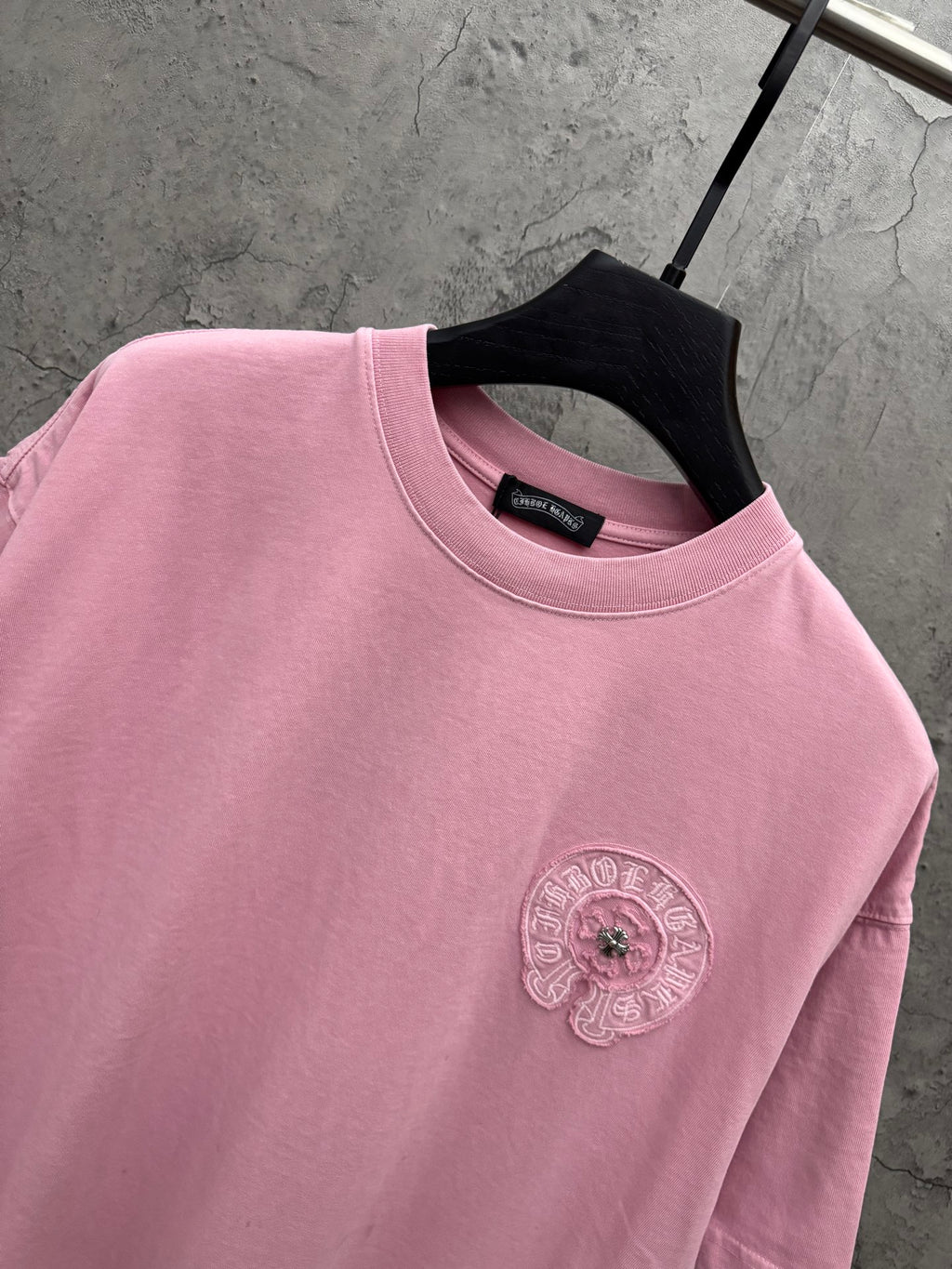 Pink crewneck T-shirt close-up of embroidered chest badge