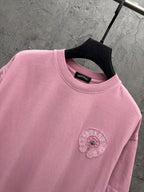 Pink crewneck T-shirt close-up of embroidered chest badge