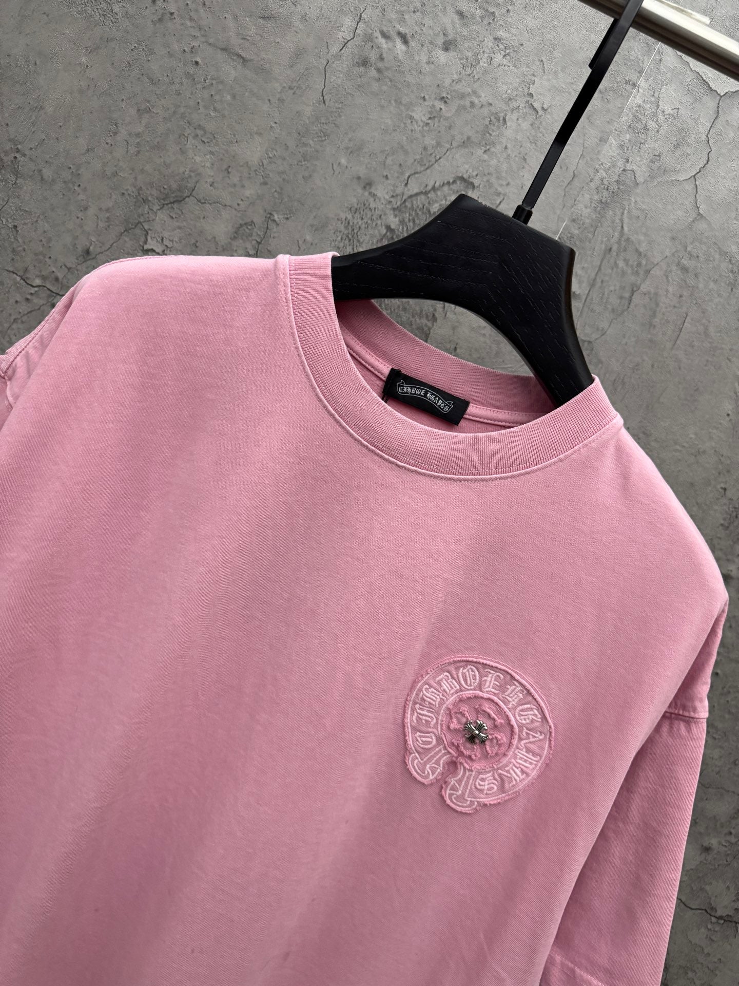 Pink crewneck T-shirt close-up of embroidered chest badge